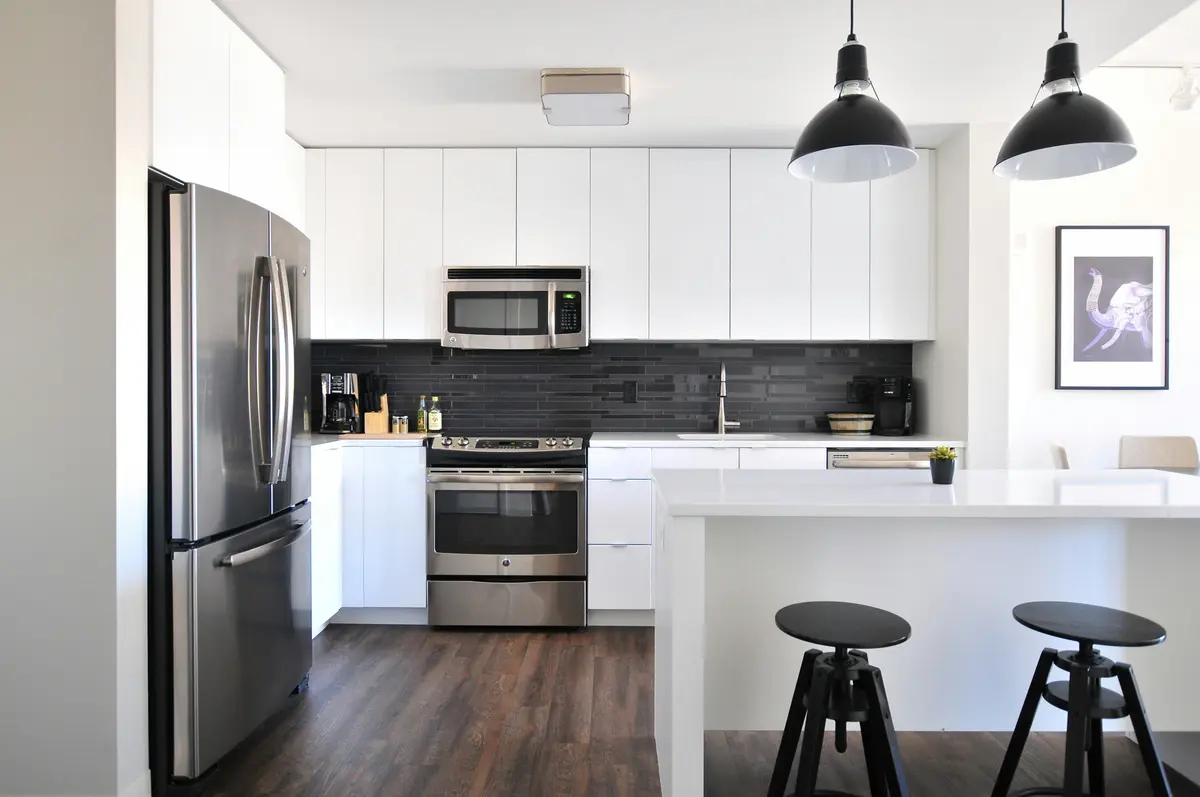 Kitchen before: plain white cabinets, black tile backsplash and basic lighting